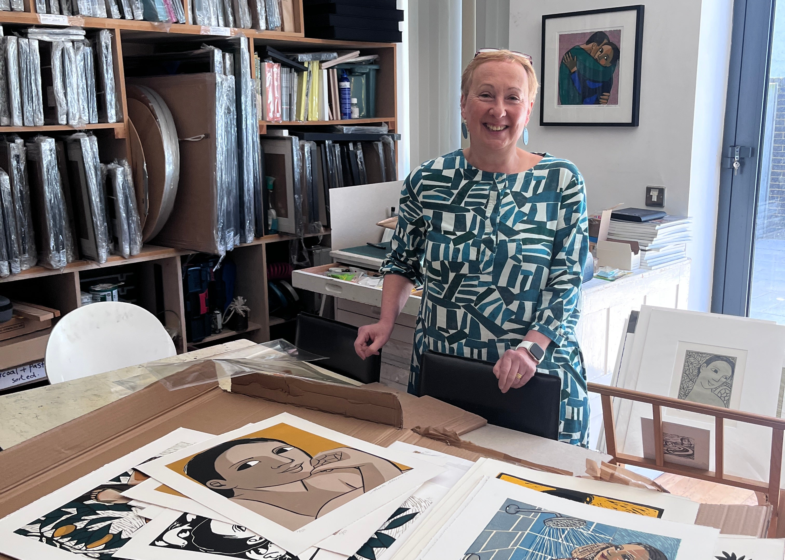 Konstnären Anita Klein i sin studio i London. Konstnären står framför ett antal verk som galleriet har köpt in. I bakgrunden syns flera inramade verk staplade på en hylla. 